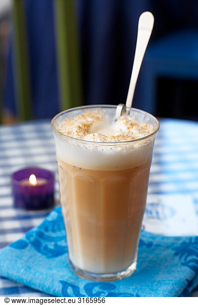 A glass of Cafe ou lait on a table.