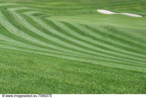 A golf course with mown fairways creating a pattern on an undulating landscape.