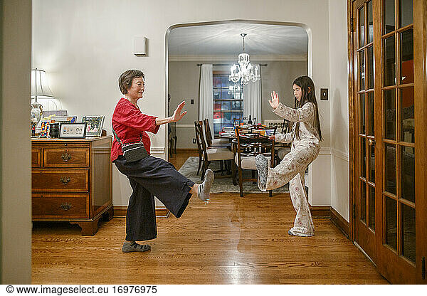 A grandmother teaches her tween granddaughter tai chi at home