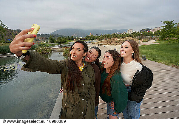 A group of beautiful women take a selfie in the city center park by a