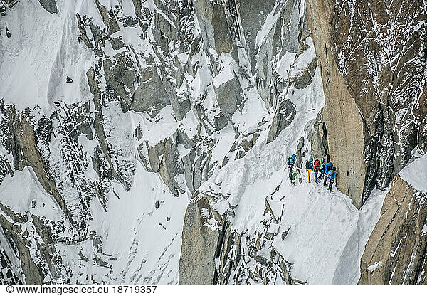 A group of climbers gathers in steep terrain below a gendarme