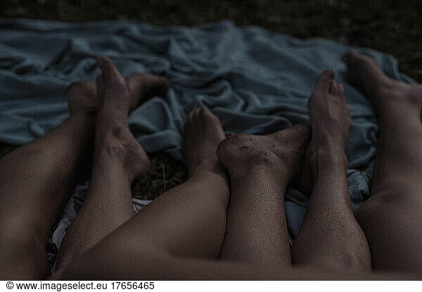 A group of dirty feet lying entwined on bed