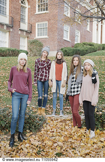 A group of five teenage girls outdoors in woolly hats and scarves.
