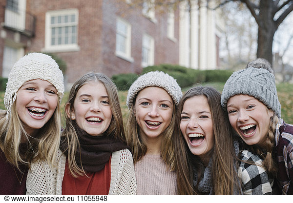 A group of five teenage girls outdoors in woolly hats and scarves.