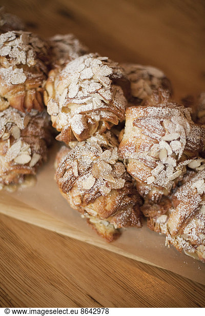 A group of fresh baked almond croissants  with icing sugar dusting. Organic party food desserts.