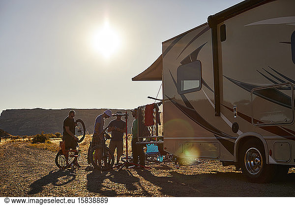 A group of guys working on mountain bikes at the rear of an RV.
