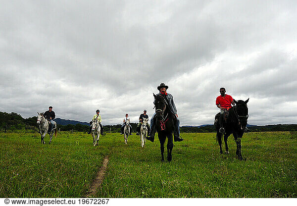 A group of horses and their riders walk through a field in the Chiapas countryside  Mexico.