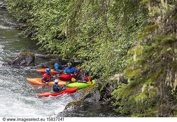 A group of kayakers take a break from paddling the Cheakamus River