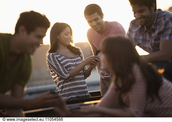 A group of men and women on a rooftop terrace having a party.