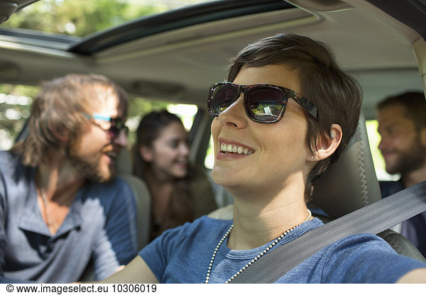 A group of people inside a car  on a road trip. View to the back seat  four passengers.