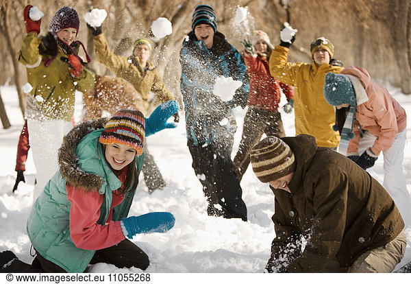 A group of young people  boys and girls having a snowball fight.