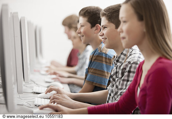A group of young people  boys and girls  students in a computer class working at screens.