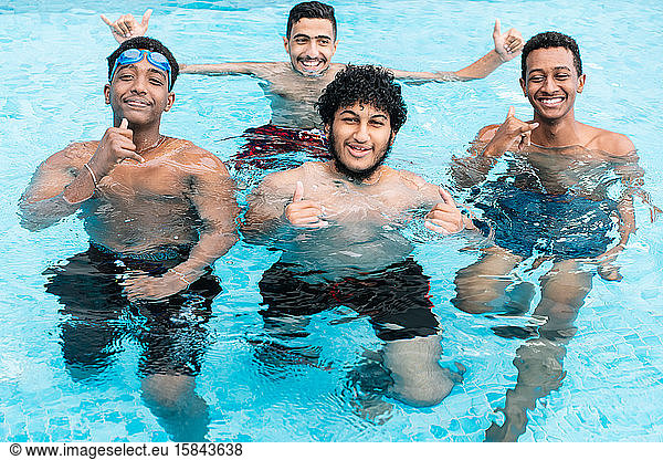 A group of young people in a pool smiling and gesturing