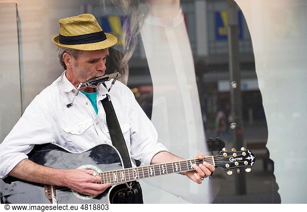 A guitarplayer is making music in front of a shop