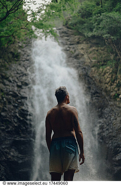 a guy looking around and feeling the nature in a waterfall