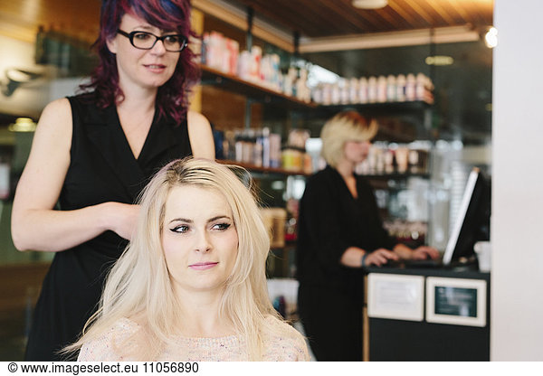 A hair stylist and a client  a young woman with long blonde hair  at a hair salon.