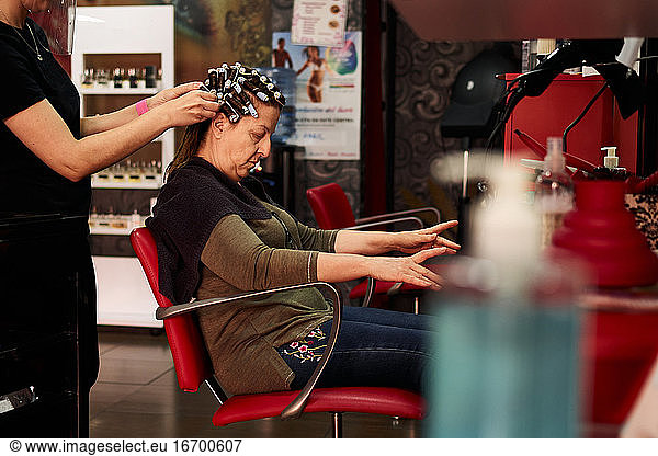 A hairdresser's client gestures with her hands while is being combed