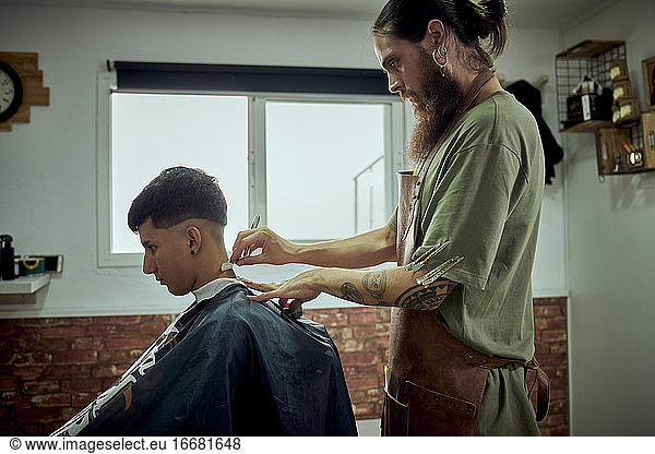 A hairdresser working with a knife on a client