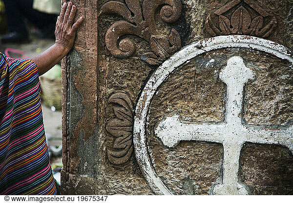 A hand and a cross in rural Guatemala.