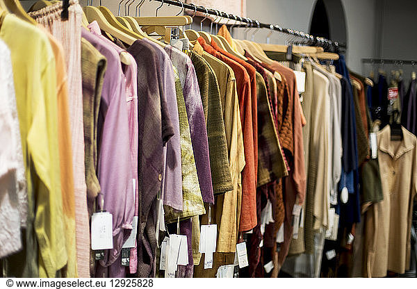 A hanging rail of women's clothing dyed using natural plant dyes  on a rail in a store.