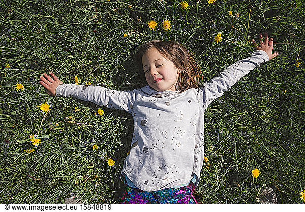 A happy child lays down in a field of wildflowers with closed eeditorial