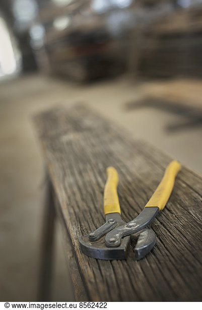 A heap of recycled reclaimed timber planks of wood. Environmentally responsible reclamation in a timber yard. A pair of pliers on a plank of wood.