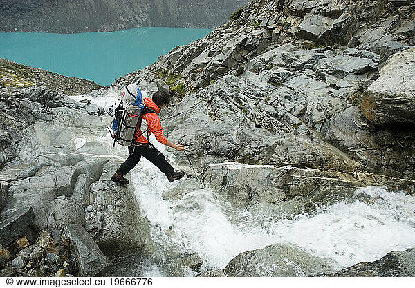 A hiker crosses a mountain stream in El Chalten  Santa Cruz  Argentina.