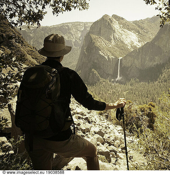 A hiker looks off in the distance at Bridal Veil Falls from the abandoned  historic Old Big Oak Flat Road in Yosemite Valley.
