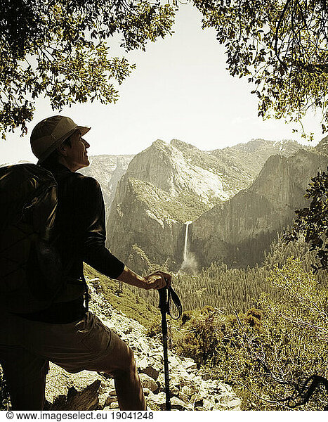 A hiker looks off in the distance at Bridal Veil Falls from the abandoned  historic Old Big Oak Flat Road in Yosemite Valley.
