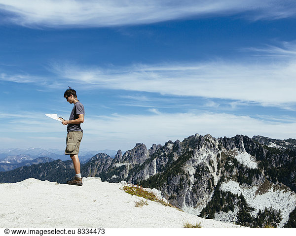 A hiker on the mountain summit  looking at a map. Surprise Mountain  Alpine Lakes Wilderness  in Mount Baker-Snoqualmie National Forest