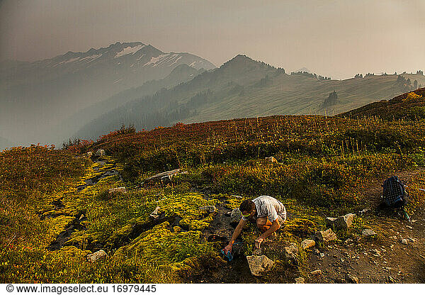 A hikers fills up water a stream while climbing Glacier Peak in WA.