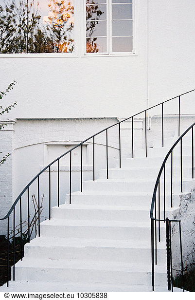 A historic late 18th century house with white walls and a curved exterior staircase