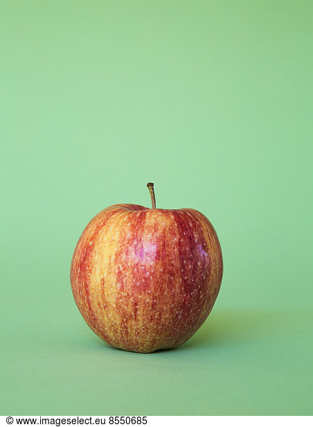 A Honey Crisp apple on a green background