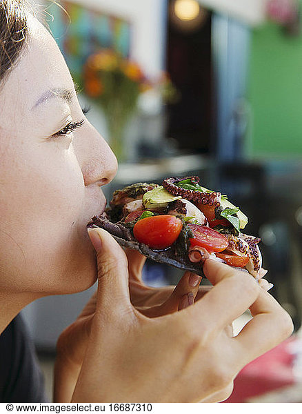 A japanese lady eats a seafood taco in San Diego