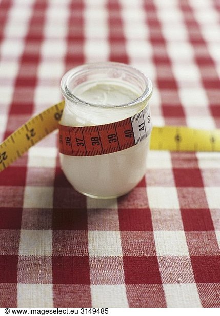 A jar of yoghurt with a tape measure wrapped around it