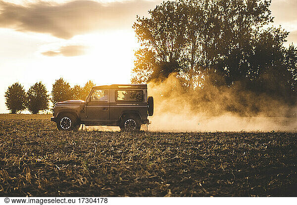 A jeep drives offroad in a field