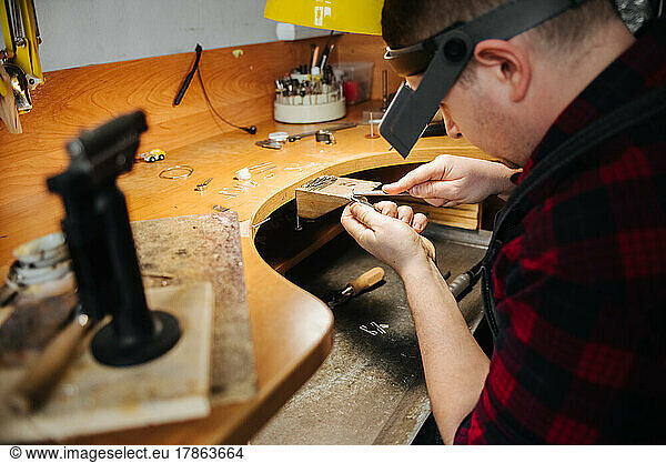 a jeweler works with a piece of jewelry  a jeweler's hands