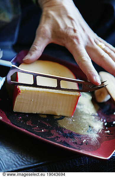 A knife cutting a slice of cheese.