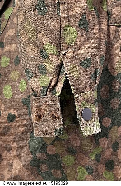 A 'Knochensack' in 'Erbstarn' camouflage pattern. Cotton cloth production from circa 1944  one side imprinted with 'Erbstarn' (pea dot) camouflage pattern. Covered button fly  Bakelite buttons (a few buttons missing)  no zippers (flaps are sewn up)  the sleeves with Prym push buttons  the reverse with a stitched-on pistol holster. Distinct marks from an SS eagle on the right of the front side. Grey inner liner. Doubtlessly an original piece and definitely one of the rarest SS uniform items  in obviously worn condition. historic  historical  20th century  1930s  1940s  Waffen-SS  armed division of the SS  armed service  armed services  NS  National Socialism  Nazism  Third Reich  German Reich  Germany  military  militaria  utensil  piece of equipment  utensils  object  objects  stills  clipping  clippings  cut out  cut-out  cut-outs  fascism  fascistic  National Socialist  Nazi  Nazi period