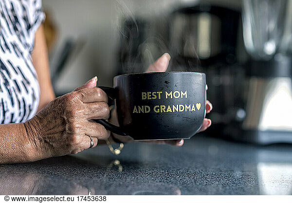 A latin grandma holding a black mug with a frase