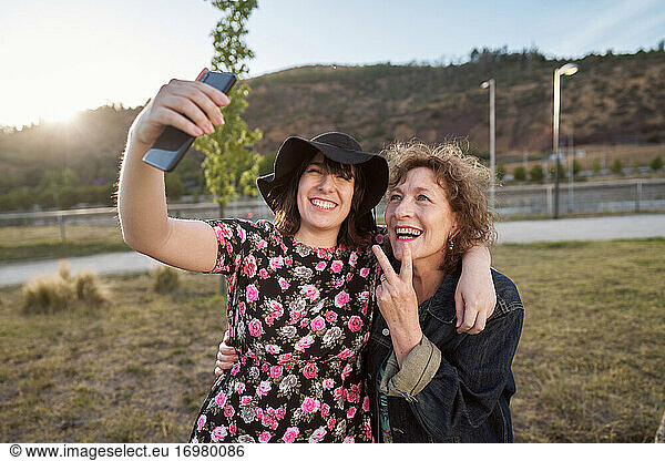 A Latina mother and daughter take a selfie photo with their cell phone