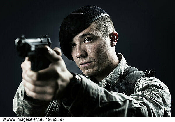 A Latino  male  Air Force Security Forces Airman in uniform poses with his M-9 pistol.