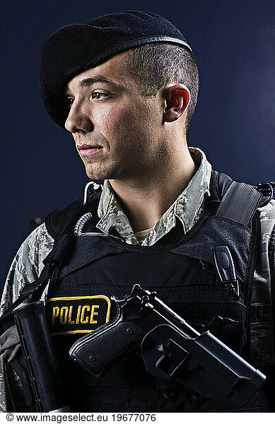 A Latino  male  Air Force Security Forces Airman in uniform poses with his M-9 pistol.