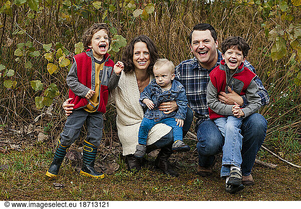 a laughing happy family sit close tether in a grassy prairie