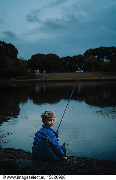 A little boy fishes in the evening.