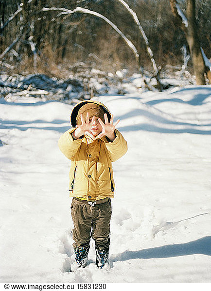 A little boy with cold hands on a snowy winter day.