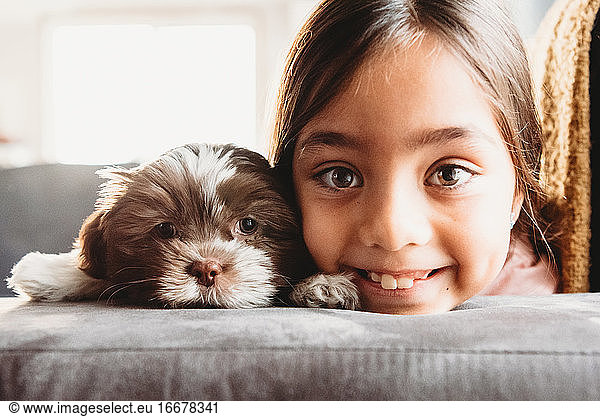 A little girl and her Shitzu puppy smiling