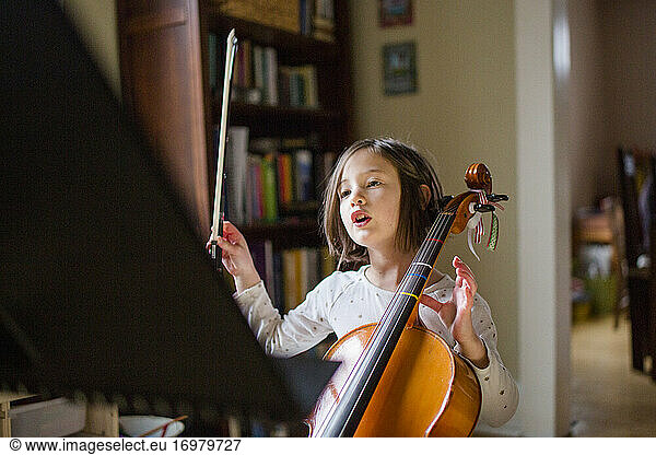 a little girl holding cello lifts her bow up in preparation to play