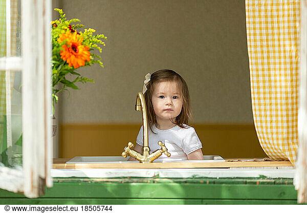A little girl is sitting in the sink in the kitchen