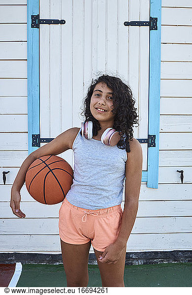 A little girl with curly hair headphones and a basketball